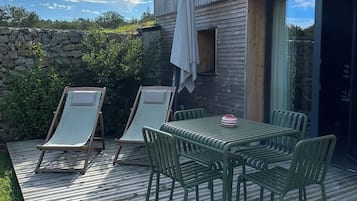 Una terraza con mesa y sillas, un muro de piedra y un edificio moderno con grandes ventanales.