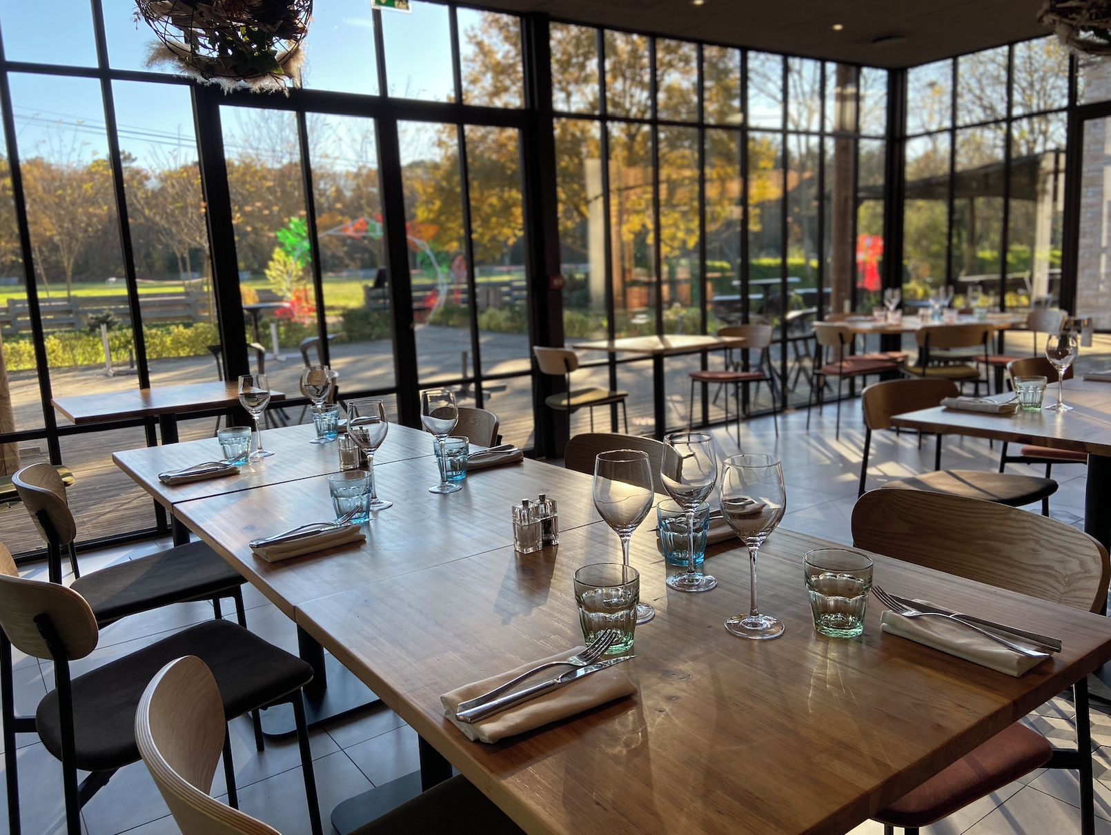 A restaurant with tables set for dining, large windows, and a view of the outdoors.