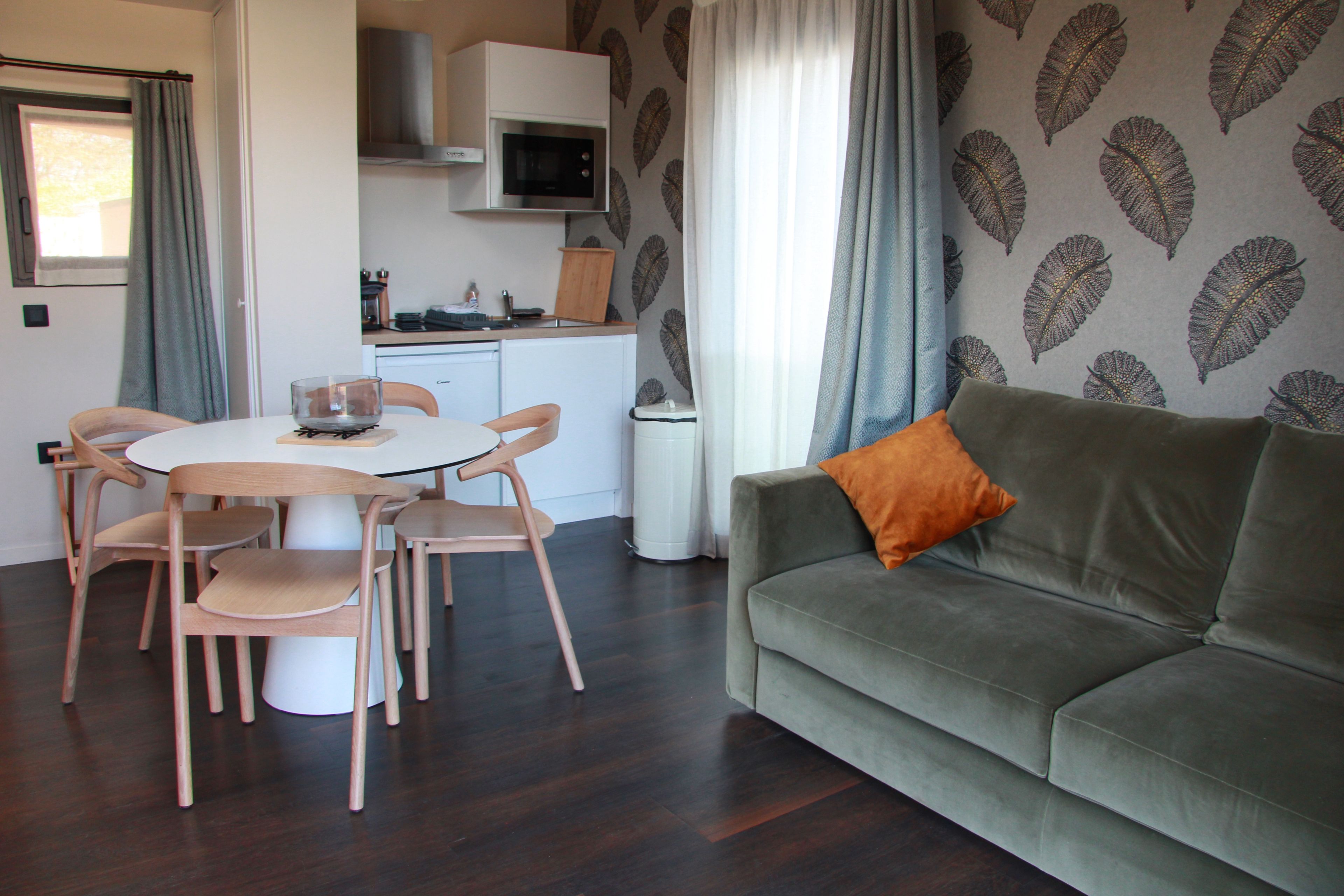A compact living space with a dining area, kitchenette, and a sofa with a cushion.