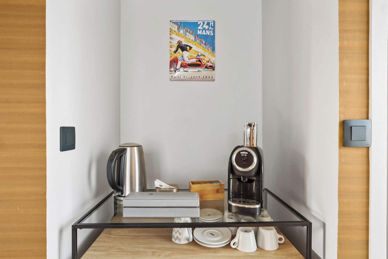 A small kitchenette with a coffee machine, a kettle, and a poster on the wall.