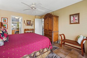 Ein Schlafzimmer mit einem Bett, einem Holzschrank, einer Bank und einem Deckenventilator.