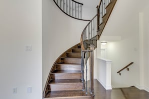 A spiral staircase with wooden steps and metal railings, leading to an upper floor.