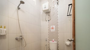A small, tiled bathroom with a shower, toilet, and a hand dryer.