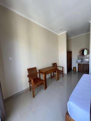 A hotel room with a bed, a table, two chairs, a sink, and a mirror. - Canggu Nadi 2  (Canggu)