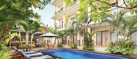 A pool area with lounge chairs and a dining area.