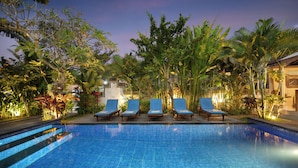 A pool area with lounge chairs and tropical plants.