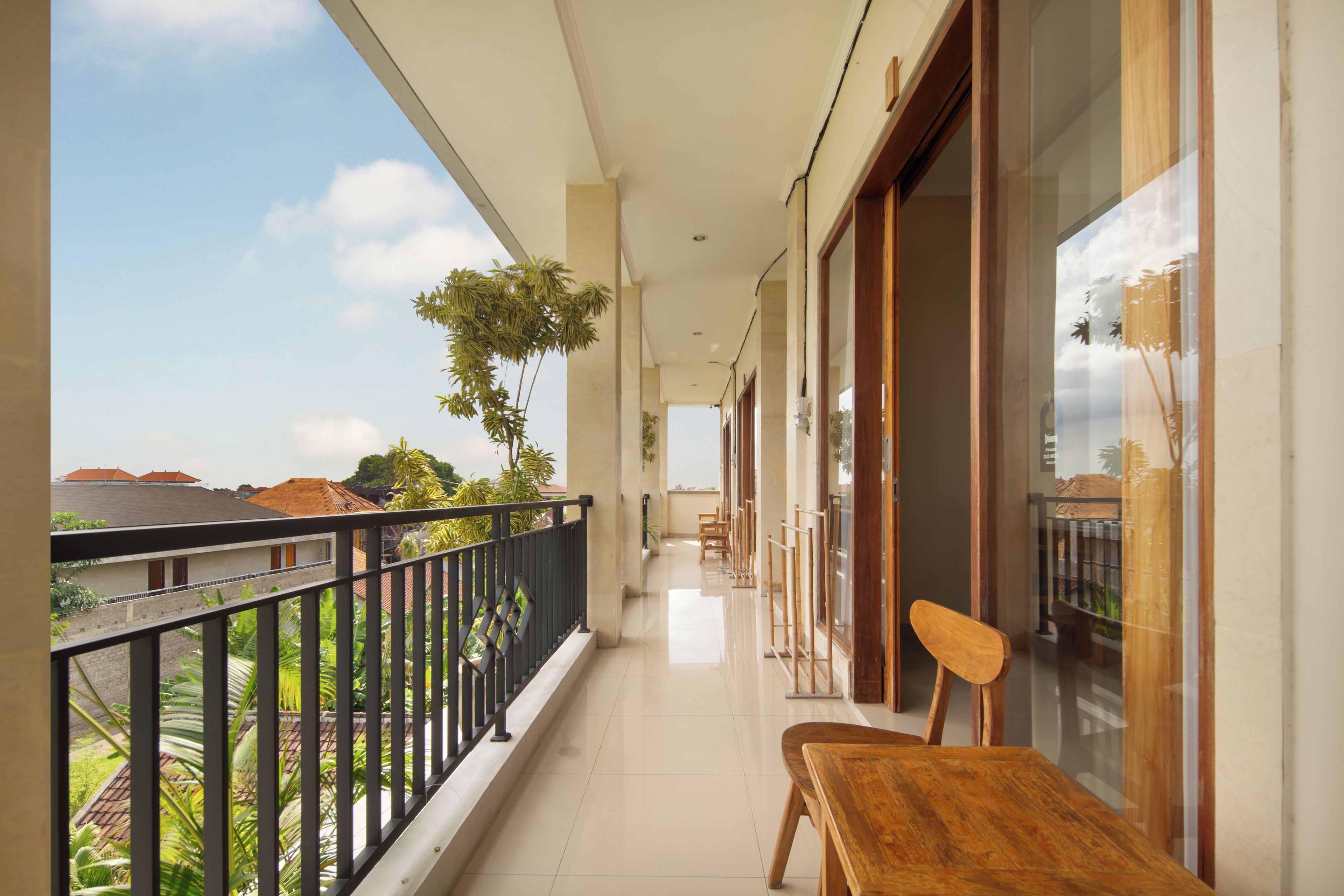 A balcony with a view of buildings and trees, a wooden chair, and a glass door.