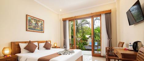 Une chambre d’hôtel dotée d’un grand lit, d’un bureau avec une chaise, d’une télévision et d’une porte-fenêtre coulissante donnant sur un espace piscine.