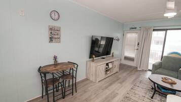 Una sala de estar con una mesa de comedor de madera, sillas, un televisor y un sofá.