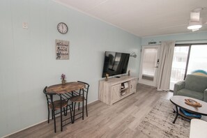 Una sala de estar con una mesa de comedor de madera, sillas, un televisor y un sofá.