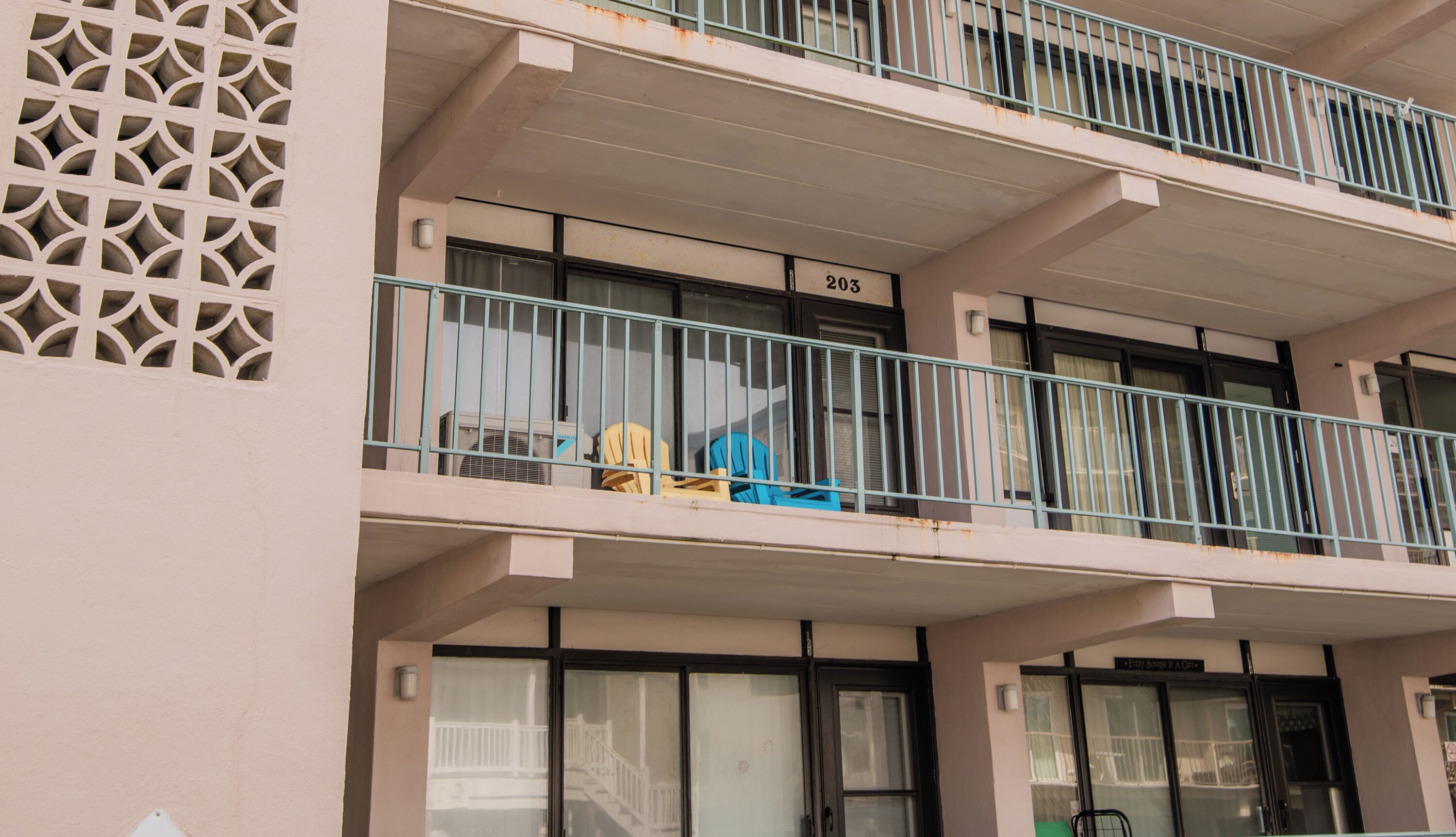 Un edificio de varios pisos con balcones, número 203, y un diseño geométrico en la fachada.