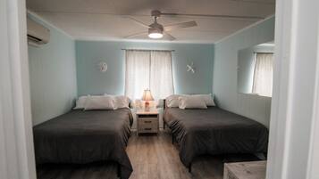 Un dormitorio con dos camas, ventilador de techo, mesita de noche y una decoración con forma de estrella de mar.