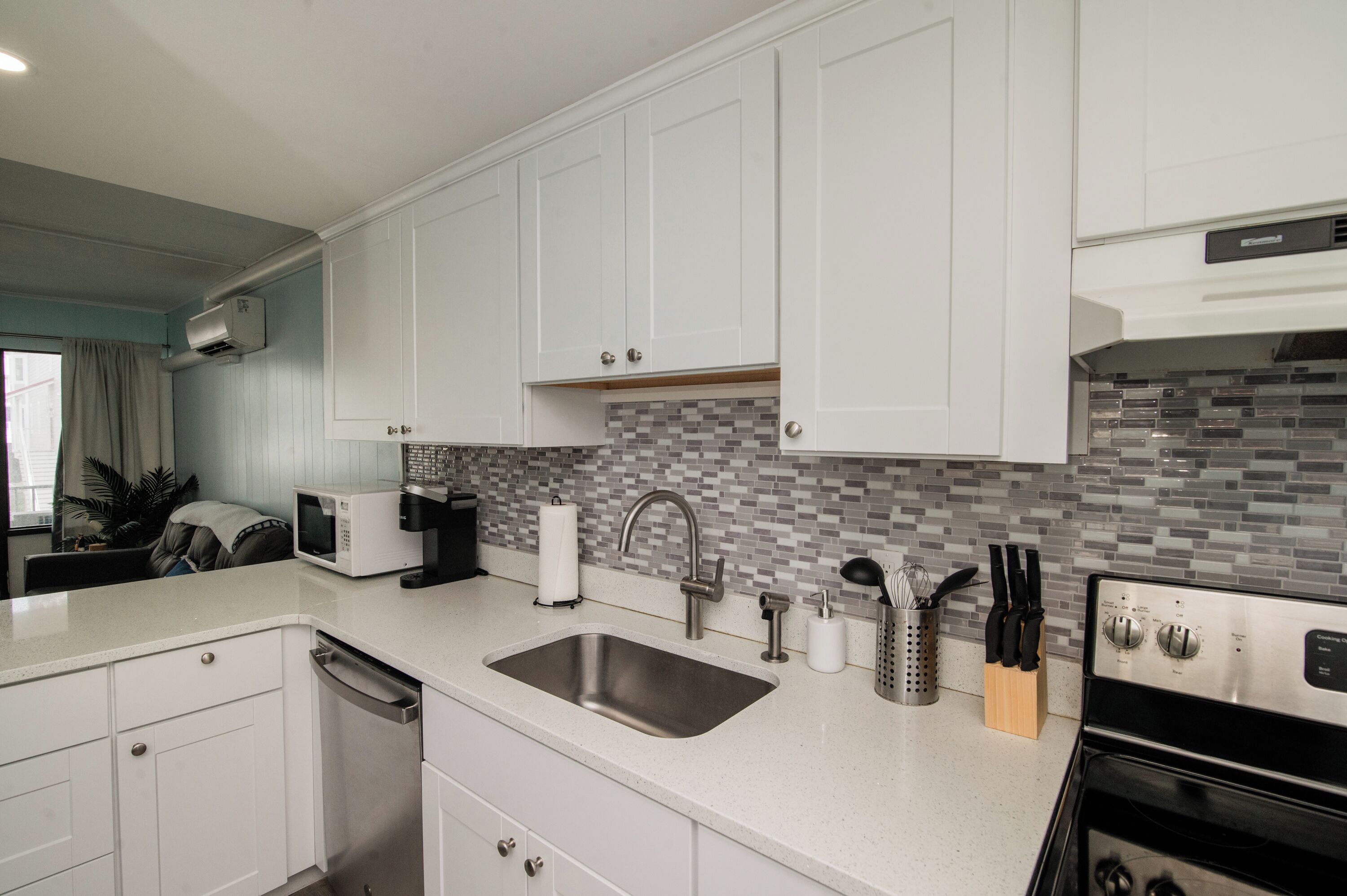 A modern kitchen with white cabinetry, a stainless steel sink, a microwave, and a built-in oven.