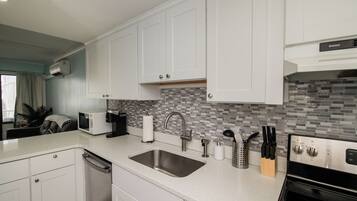 A modern kitchen with white cabinetry, a stainless steel sink, a microwave, and a built-in oven.