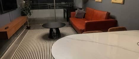 Una sala moderna con un sofá, una mesa redonda y un televisor.