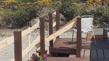 A wooden deck with a chair and a planter with flowers.