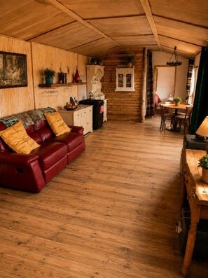 Ein gemütliches Wohnzimmer mit einer roten Ledersofa, Holzwänden und einem Essbereich mit Tisch und Stühlen.