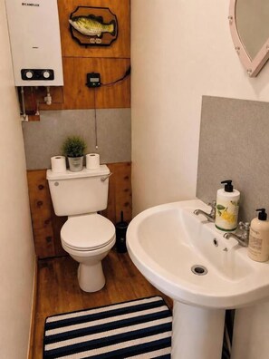 Ein kleines Badezimmer mit Toilette, Waschbecken und einer Holzwand mit einer Fischdekoration.