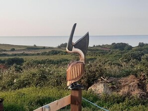 A wooden sculpture of a bird perched on a fence.