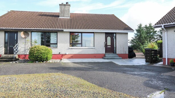 A two-story house with a red-tiled roof, a satellite dish, and a small front yard with gravel and a bush. - 7 Creag Ruadh (Isle of Lewis)