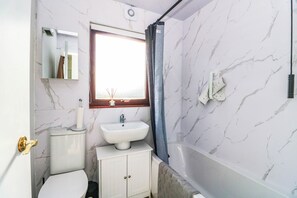 Un baño con inodoro, lavamanos y bañera.