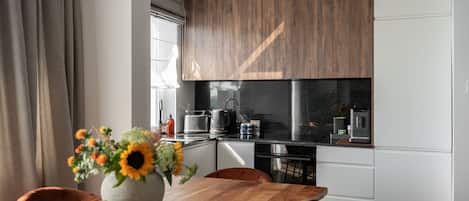 A modern kitchen with wooden cabinets, a black countertop, and a dining area with a wooden table and chairs.