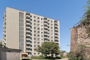 A high-rise residential building with multiple balconies and a brick structure to the right. - Secret Garden by Lion Apartments Gdańsk (Gdańsk)