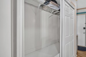 Ein weißer Schrank mit Kleiderstange und einer Tür mit Griff.