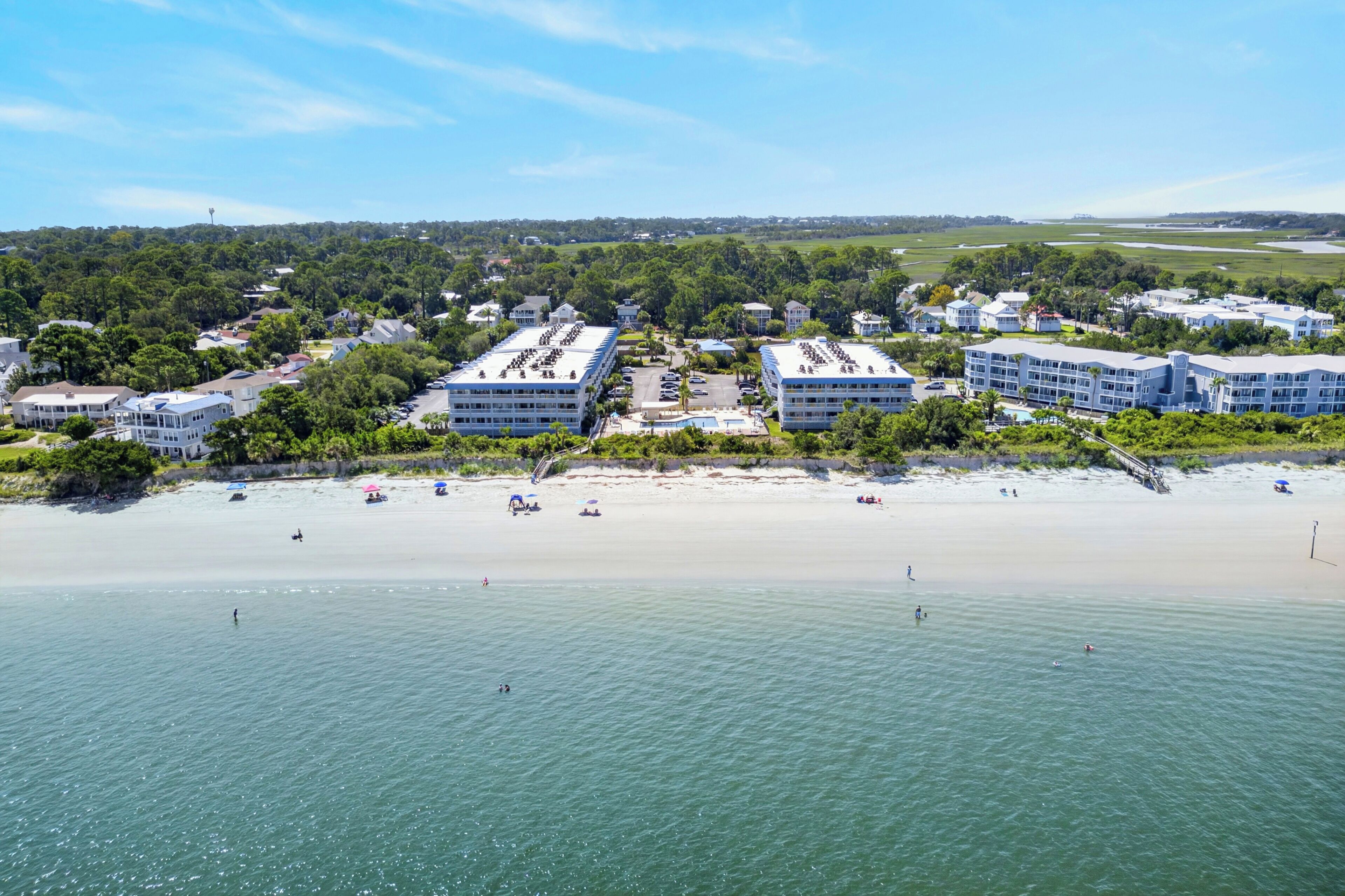 A coastal hotel with multiple buildings, a beach, and a view of the ocean.