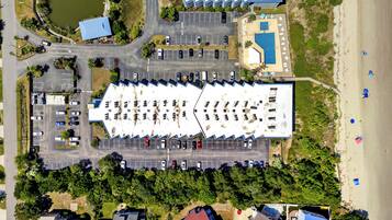 Eine Vogelperspektive eines Anwesens mit großem Parkplatz, einem Swimmingpool und einem Strandbereich.