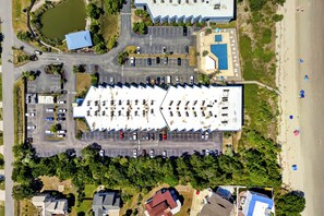 Eine Vogelperspektive eines Anwesens mit großem Parkplatz, einem Swimmingpool und einem Strandbereich.