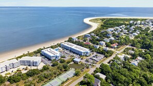 Ovenfra set udsigt over et kystnært boligområde med strand, et stort hotelkompleks og en tennisbane.