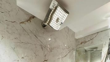 Een moderne badkamer met een marmeren vloer, een inbouw wastafel, een spiegel en een douchekop.