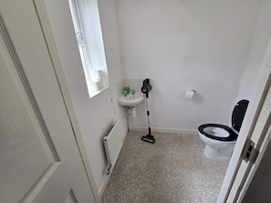 A small bathroom with a toilet, a sink, a window, and a radiator. - Shirebrook 2-bed Townhouse, With Free Parking, Ideal for Contractors and Families (Mansfield)