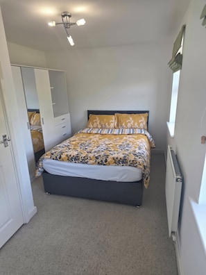 A bedroom with a bed, a wardrobe, a ceiling light, and a radiator. - Shirebrook 2-bed Townhouse, With Free Parking, Ideal for Contractors and Families (Mansfield)