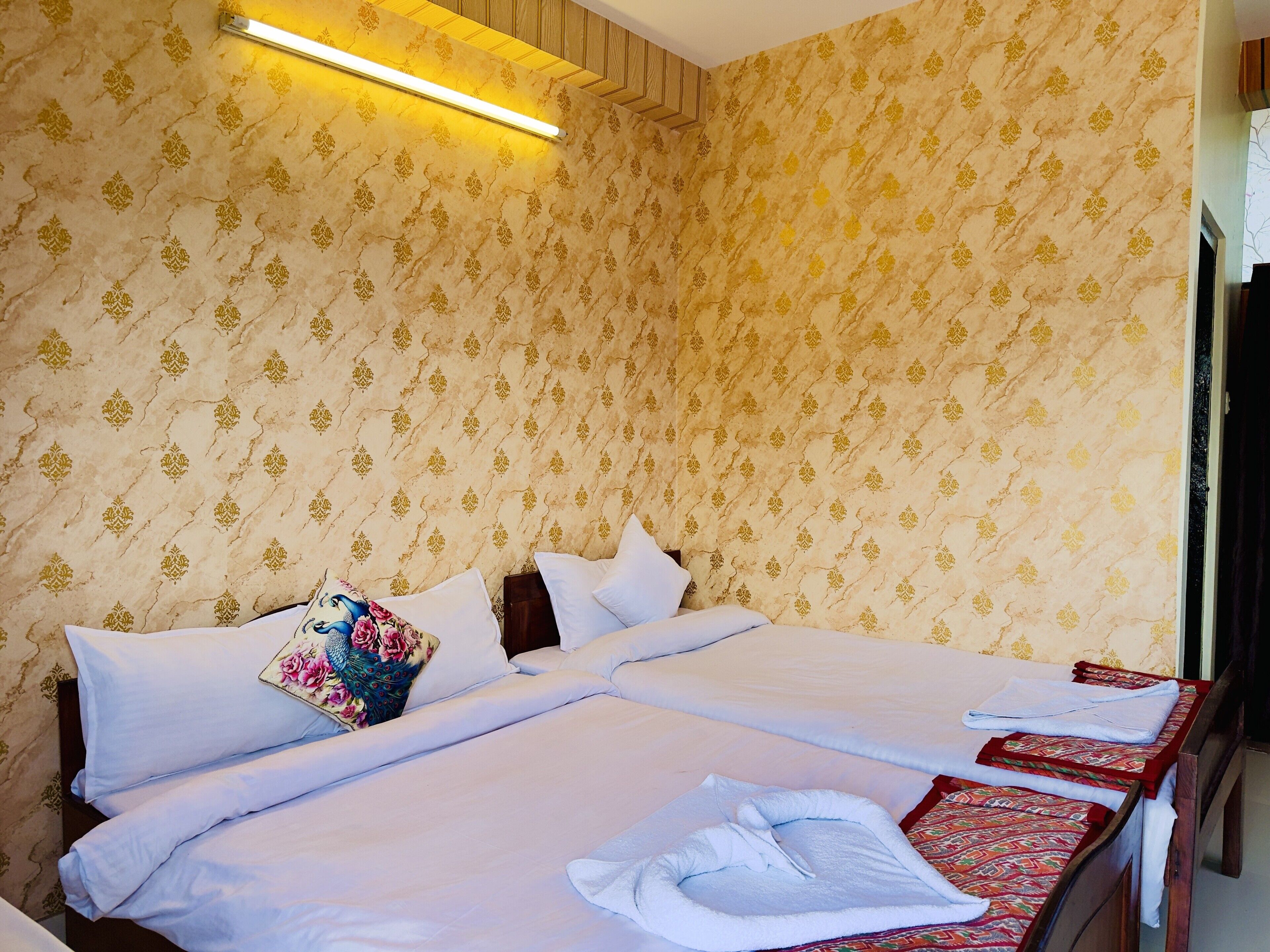 A hotel room with a large bed, two pillows, a bedside table, and a wall-mounted light.