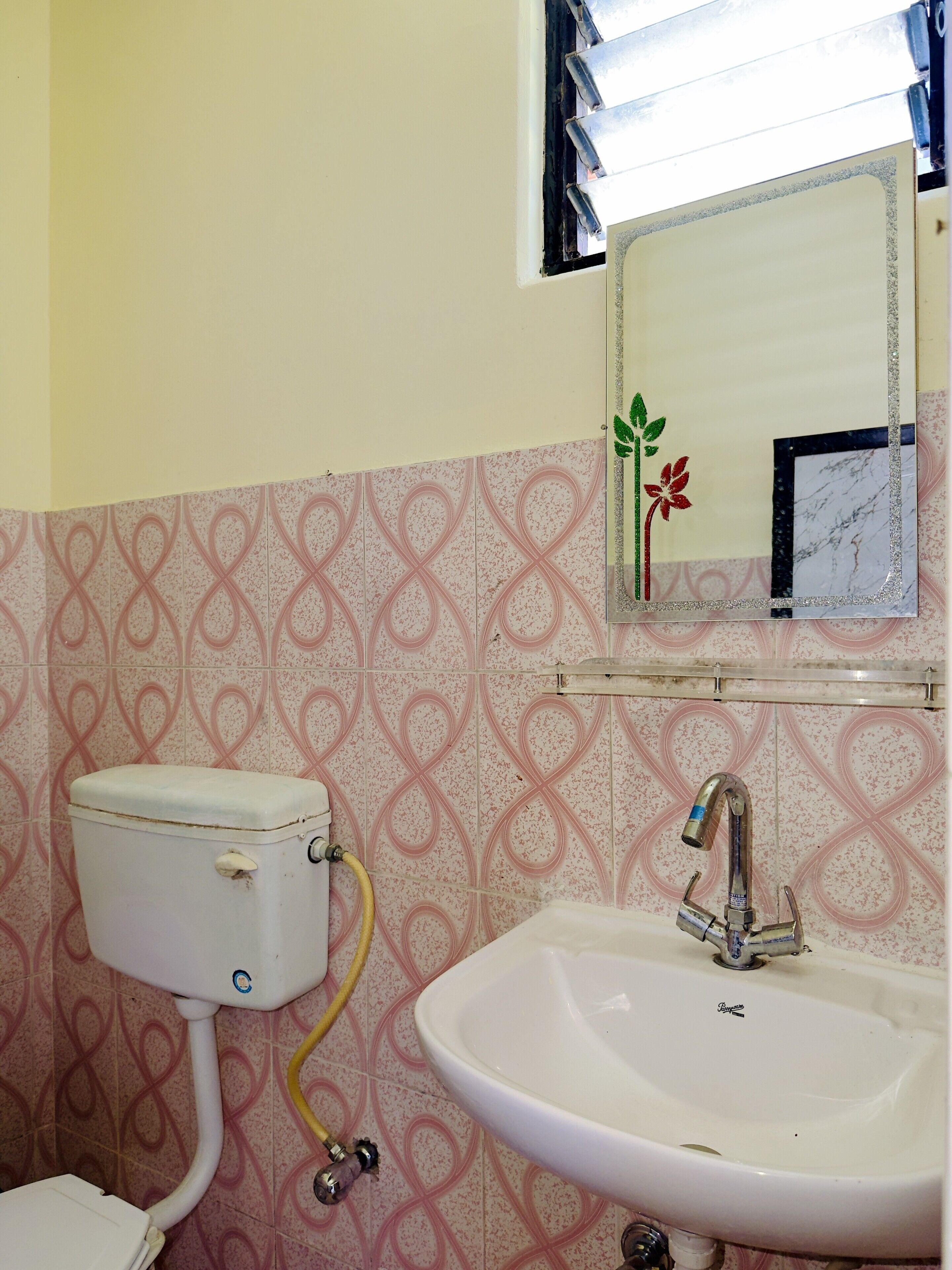 A bathroom with a toilet, sink, and a mirror with a decorative frame.