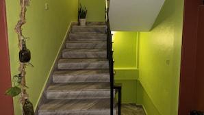 Una escalera con barandilla, una planta en maceta en la parte superior y una pared con textura.
