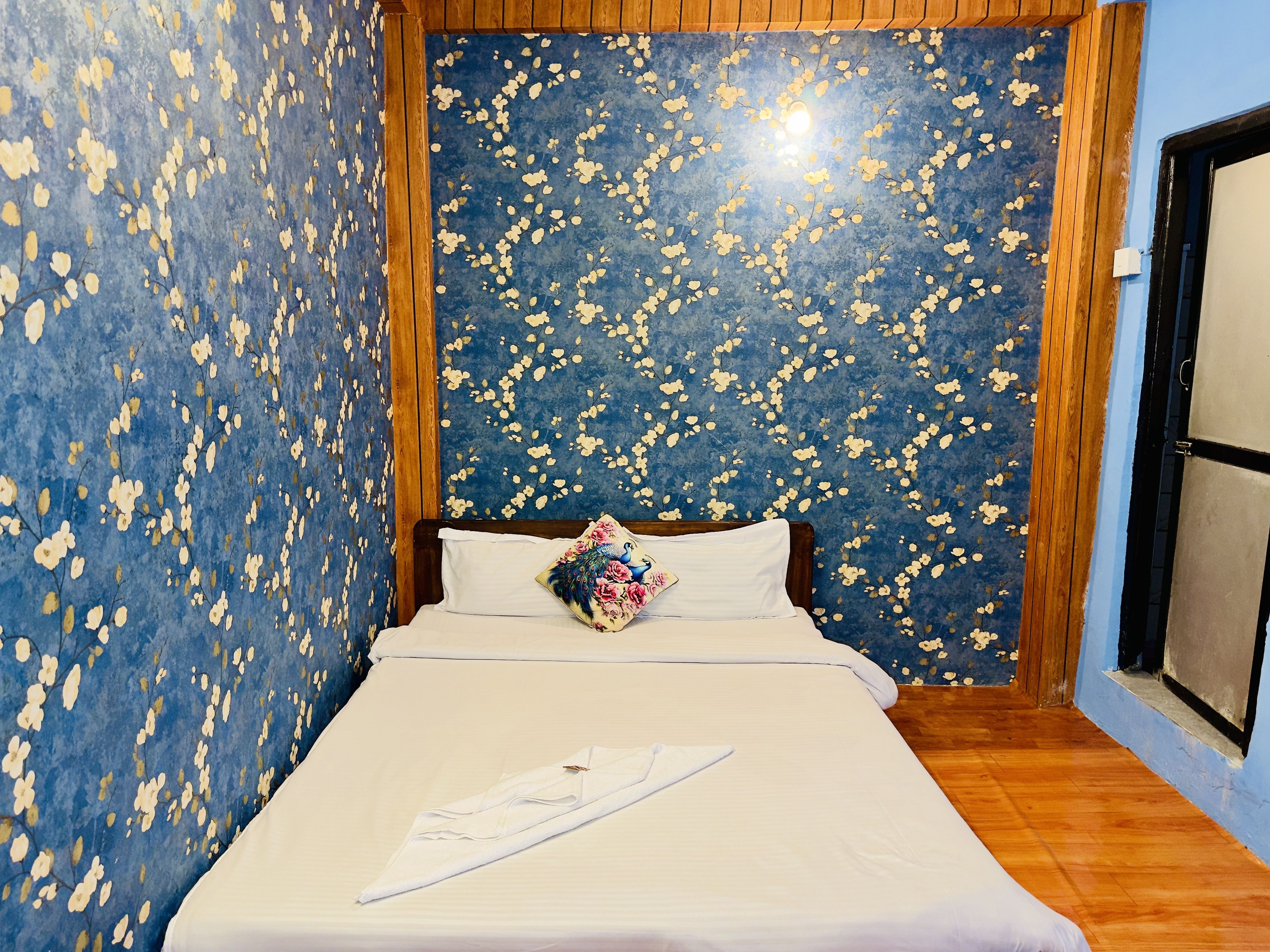 A bedroom with a bed, a pillow, and a wall with a floral pattern.