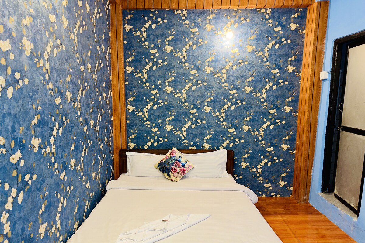 Ein Schlafzimmer mit einem Bett, einem Kopfkissen und einer Wand mit einem Blumenmuster.