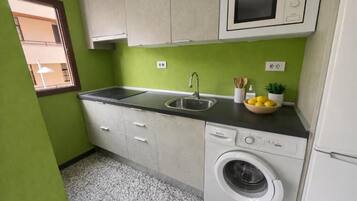 Cocina compacta con lavadora, lavamanos y microondas.