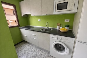 Cuina compacta amb rentadora, rentapeus i microones.