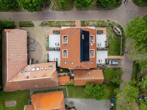 Vue aérienne d’un bâtiment doté de plusieurs sections de toit, d’espaces de détente en plein air et d’un parking.