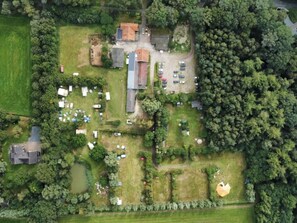 Vista aerea di una proprietà con un’area di parcheggio, diversi edifici e vegetazione circostante.