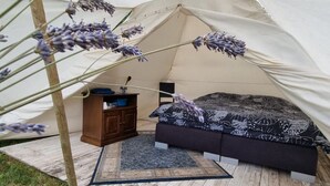 Ein Zelt mit Bett, Kommode und Teppich.