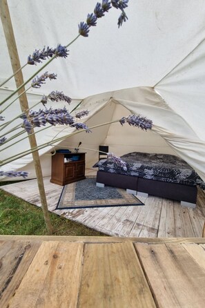 Una tenda con un letto, una cassettiera e un tappeto.