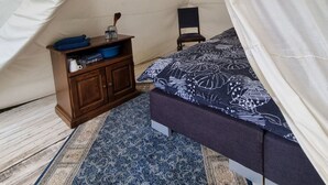 Ein Zelt mit einem Bett, einem kleinen Tisch und einem Stuhl im Inneren.