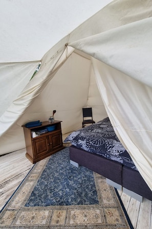 Una tenda con un letto, un tavolino e una sedia all'interno.
