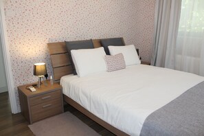 A neatly made bed with white bedding, a wooden headboard, and a bedside table with a lamp and a bottle. -  1-bedroom bungalow Limassol Countryside Tranquil Getaway Shared Pool Near Beach (Limassol)