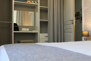Ett hotellrum med en säng, ett sängbord, en lampa, en garderob och en dörr.